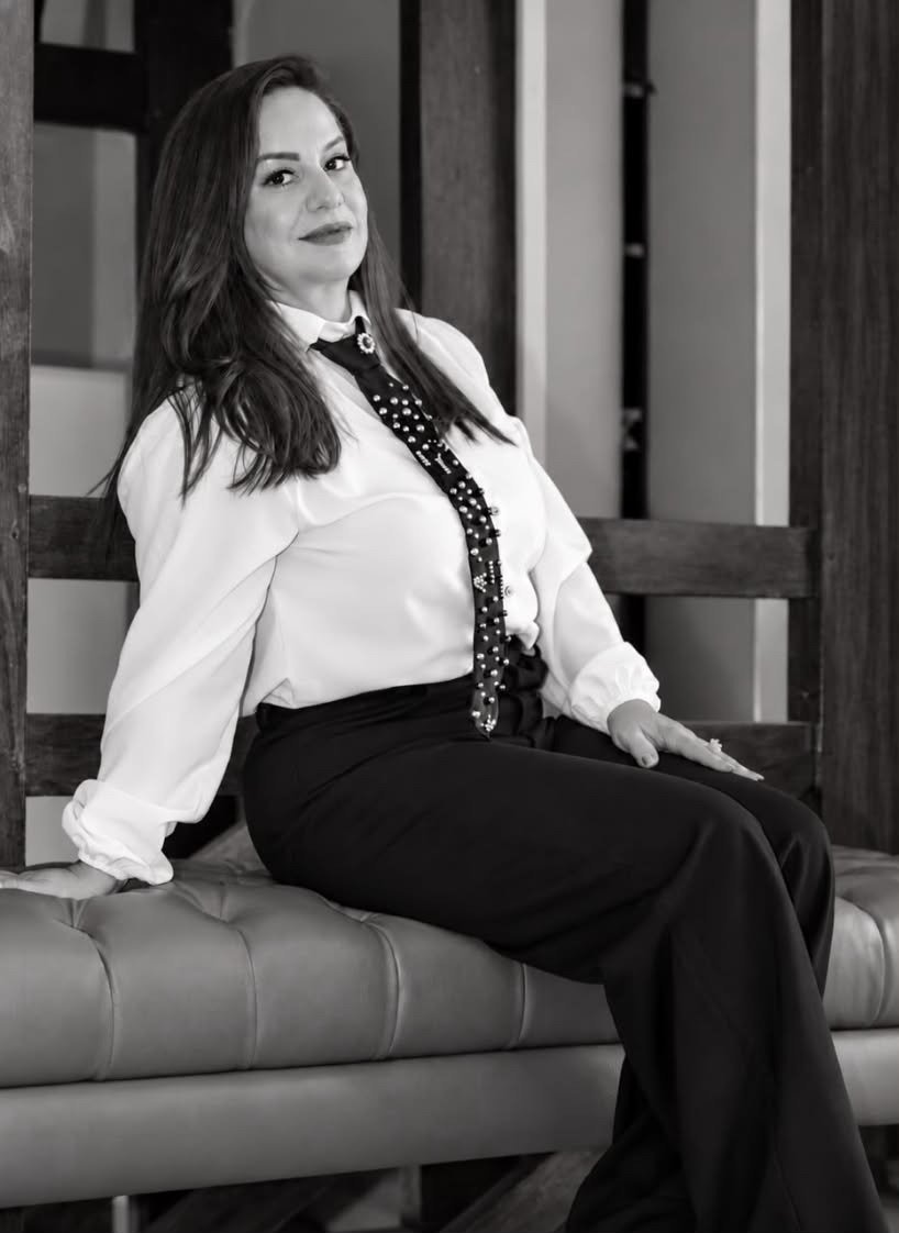 Michelle Pires sentada em um banco de couro, de camisa branca e gravata bordada, em retrato em preto e branco