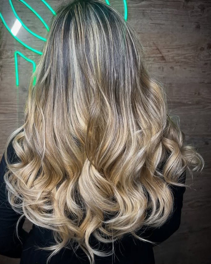 Cabelo longo loiro iluminado, com raiz natural mais escura e ondas nas pontas, visto de costas